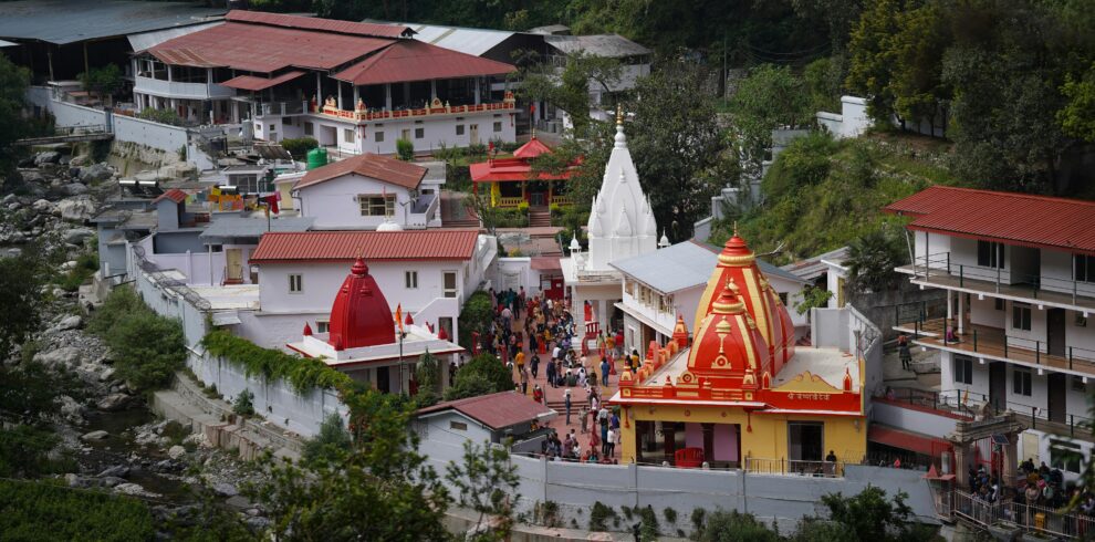 A vibrant aerial shot of the famous Kainchi Dham Temple complex surrounded by lush greenery in Uttarakhand.