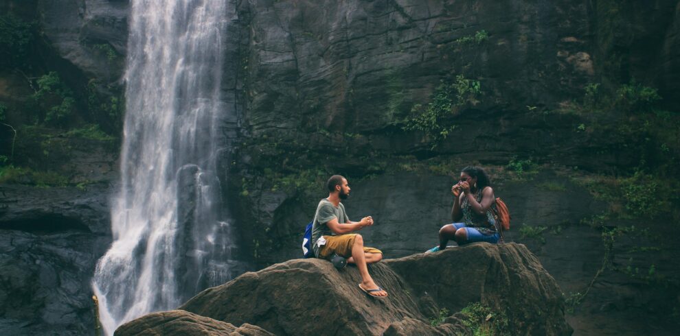 A serene moment captured by a waterfall in India with a couple enjoying nature's beauty together.