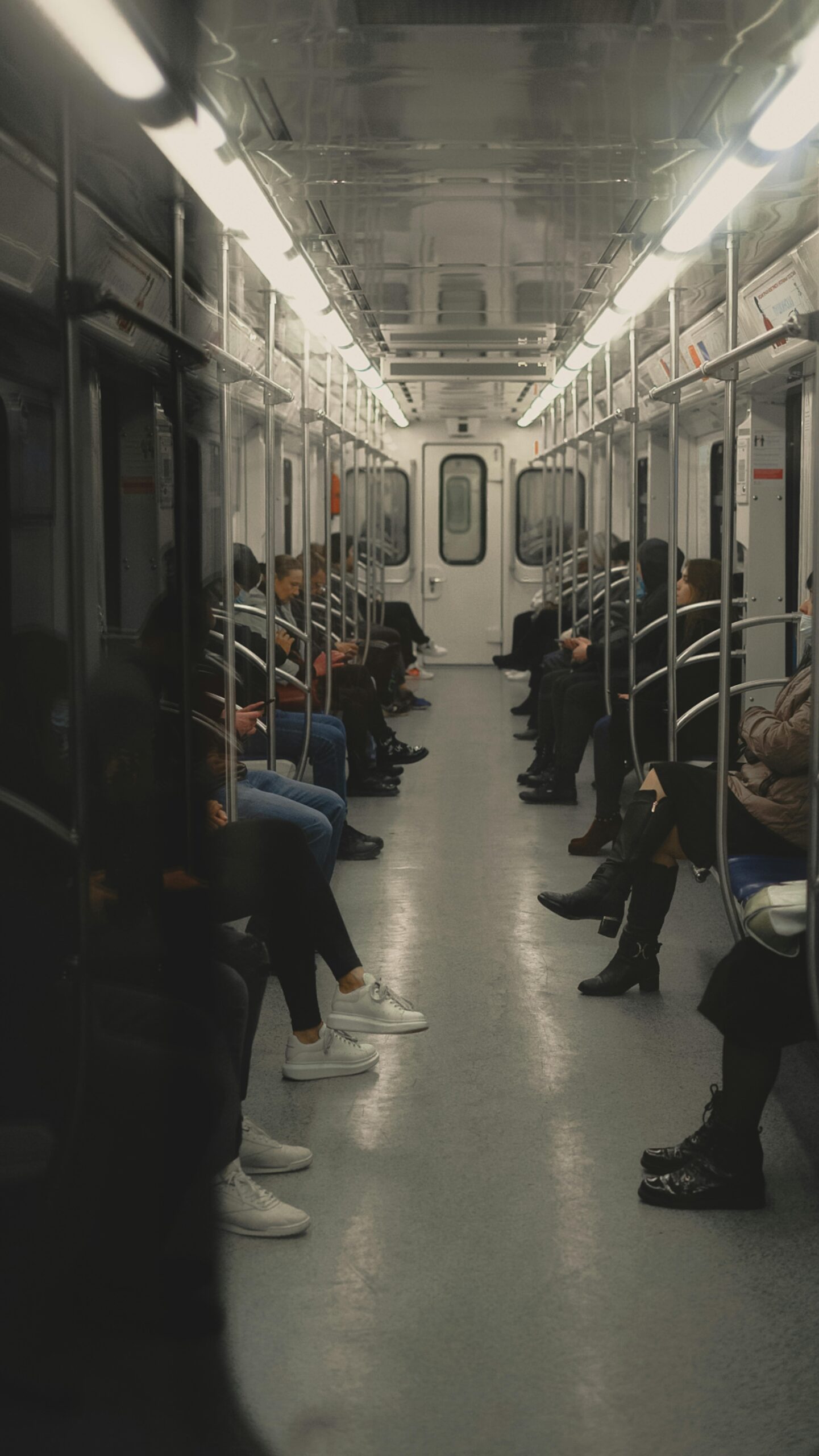 An interior view of a subway train with seated commuters during a quiet journey.